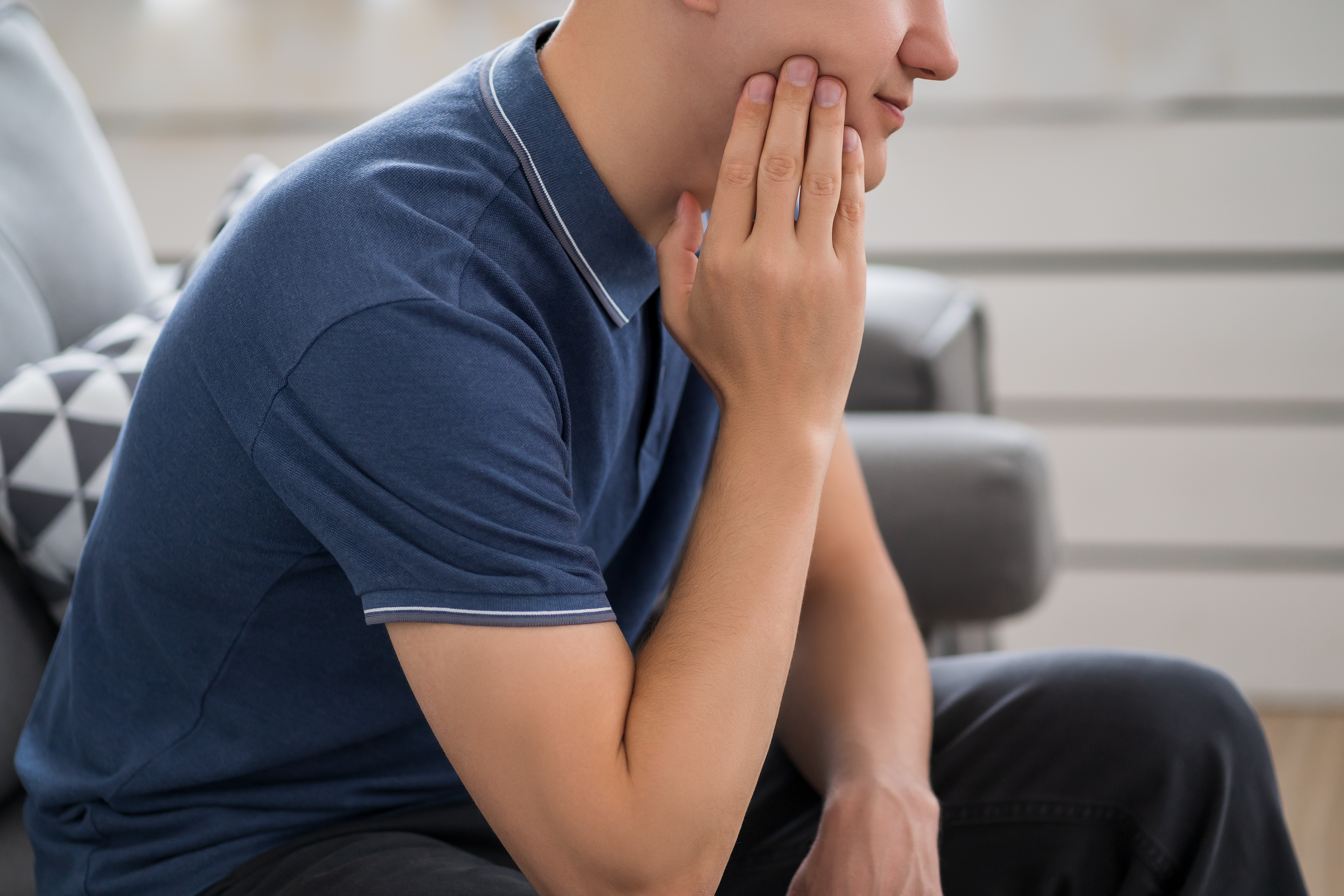 Man holding jaw after a dental procedure, experiencing numbness